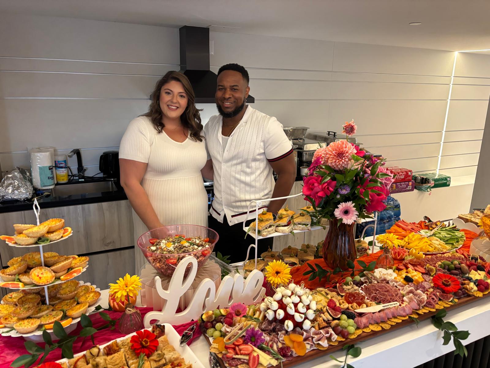 A happy couple celebrating their engagement next to a custom floral centerpiece designed by Ficus Flora