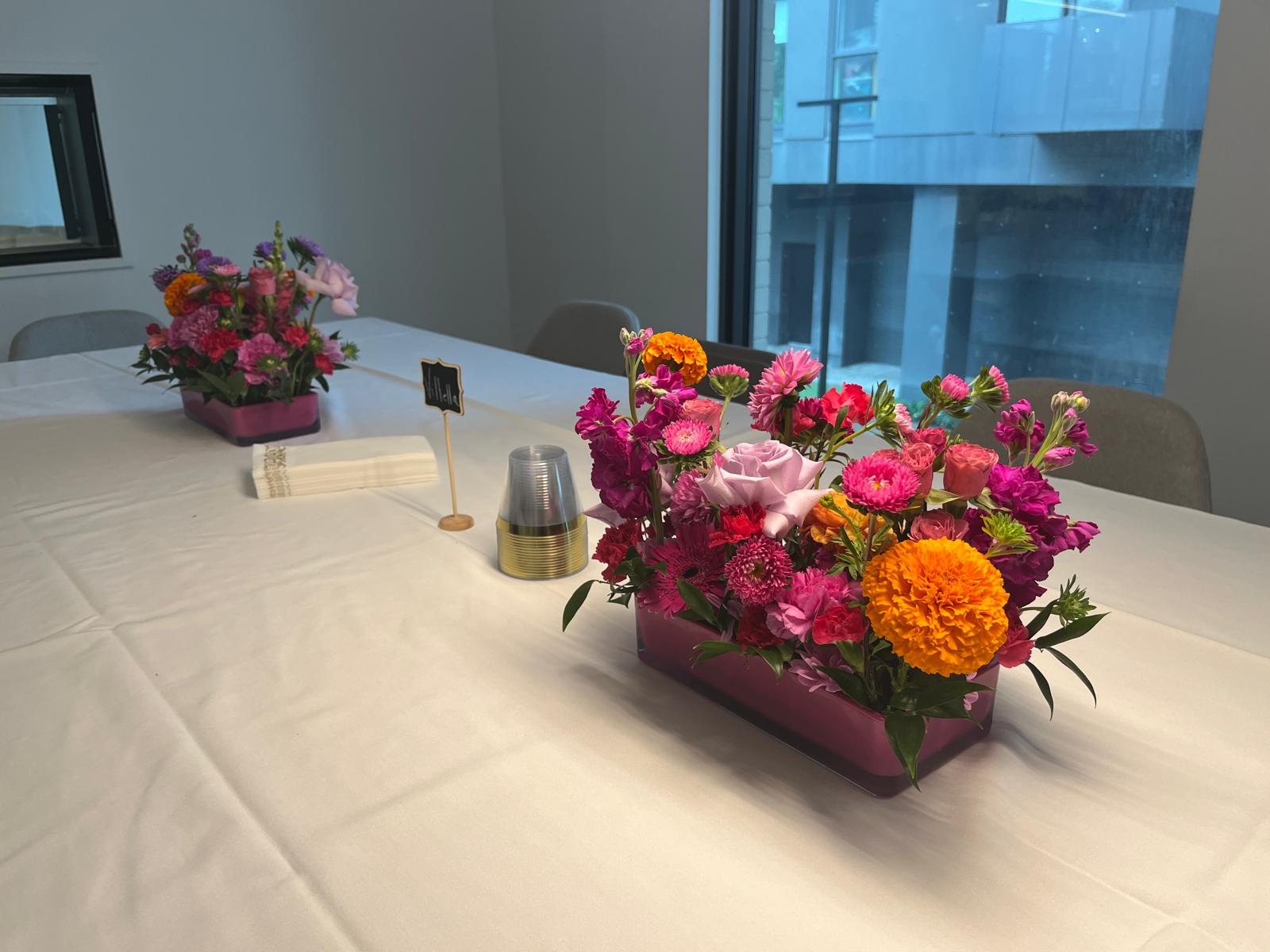 Vibrant low-profile floral centerpieces decorating a long guest table for a celebratory event in Toronto